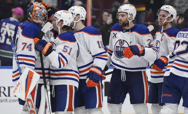 Edmonton Oilers goalie Stuart Skinner, from left to right, Troy Stecher, Zach Hyman, Leon Draisaitl and Connor McDavid celebrate after Edmonton defeated the Vancouver Canucks 7-3 during an NHL hockey game in Vancouver, on Saturday, November 9, 2024. (Darryl Dyck/The Canadian Press via AP)