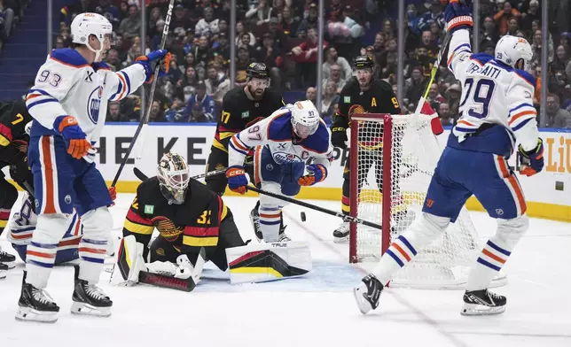 Edmonton Oilers' Leon Draisaitl (29) and Ryan Nugent-Hopkins (93) celebrate Draisaitl's goal against Vancouver Canucks goalie Kevin Lankinen (32) as Filip Hronek (17) checks Edmonton's Connor McDavid (97), during the first period of an NHL hockey game in Vancouver, on Saturday, November 9, 2024. (Darryl Dyck/The Canadian Press via AP)