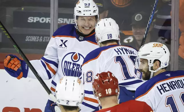 Edmonton Oilers' Jeff Skinner, left, celebrates after his goal with teammate Zach Hyman, center, during first-period NHL hockey game action against the Calgary Flames in Calgary, Alberta, Sunday, Nov. 3, 2024. (Jeff McIntosh/The Canadian Press via AP)