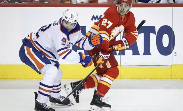 Edmonton Oilers' Vasily Podkolzin, left, checks Calgary Flames' Matthew Coronato, right, during second-period NHL hockey game action in Calgary, Alberta, Sunday, Nov. 3, 2024. (Jeff McIntosh/The Canadian Press via AP)