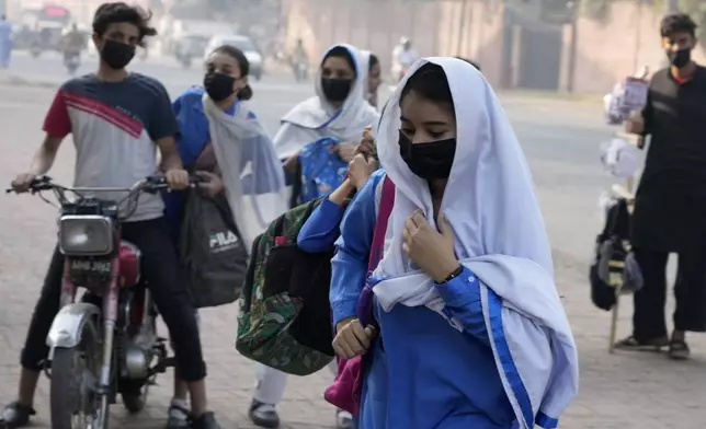 Students wear mask to protect themselves from poor air quality due to increasing smog in the city as they arrive at their school, in Lahore, Pakistan, Monday, Nov. 4, 2024. (AP Photo/K.M. Chaudary)