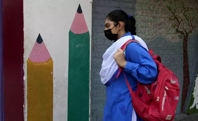 A student wears mask to protect herself from poor air quality due to increasing smog in the city as she heads to school, in Lahore, Pakistan, Monday, Nov. 4, 2024. (AP Photo/K.M. Chaudary)