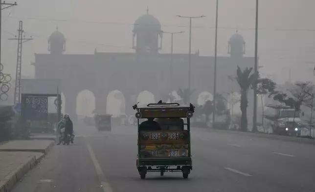 A motorcycle-rickshaw drives on a road as smog envelops the areas of Lahore, Pakistan, Wednesday, Nov. 6, 2024. (AP Photo/K.M. Chaudary)