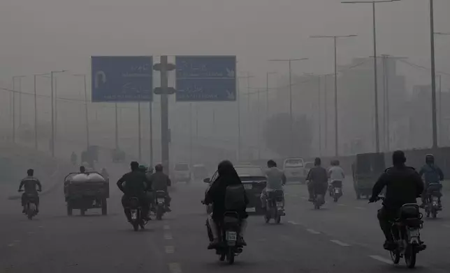 Motorcyclists drive on a highway as smog envelops the areas of Lahore, Pakistan, Wednesday, Nov. 6, 2024. (AP Photo/K.M. Chaudary)