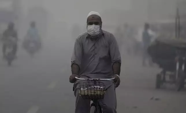 A cyclist, wearing mask, heads to his workplace as smog envelops the areas of Lahore, Pakistan, Wednesday, Nov. 6, 2024. (AP Photo/K.M. Chaudary)