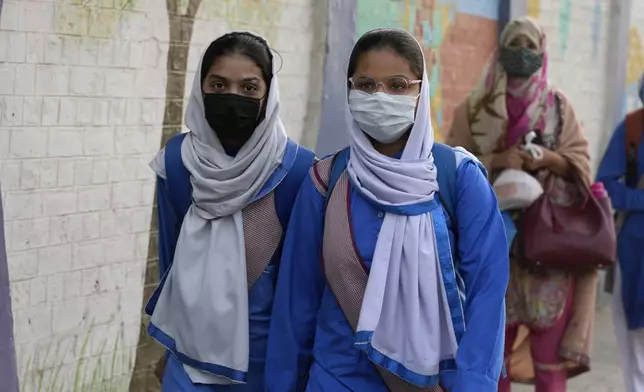 Students wear mask to protect themselves from poor air quality due to increasing smog in the city as they head to their school, in Lahore, Pakistan, Monday, Nov. 4, 2024. (AP Photo/K.M. Chaudary)