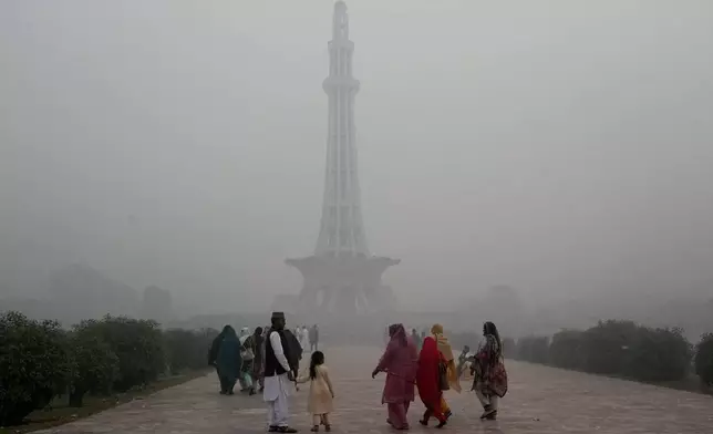 Families arrive at Minar-e-Pakistan or Pakistan monument in the morning as smog envelops the area of Lahore, Pakistan, Friday, Nov. 8, 2024. (AP Photo/K.M. Chaudary)