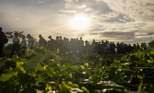 Migrants line up to board boats to continue their journey north to the United States after walking across the Darien Gap from Colombia, in Bajo Chiquito, Panama, Saturday, Nov. 9, 2024. (AP Photo/Matias Delacroix)