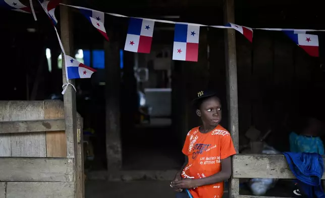 Order Was, of Ghana, waits for his father outside a shop in Bajo Chiquito, Panama, where they arrived after crossing the Darin Gap on their way to the United States, Friday, Nov. 8, 2024. (AP Photo/Matias Delacroix)