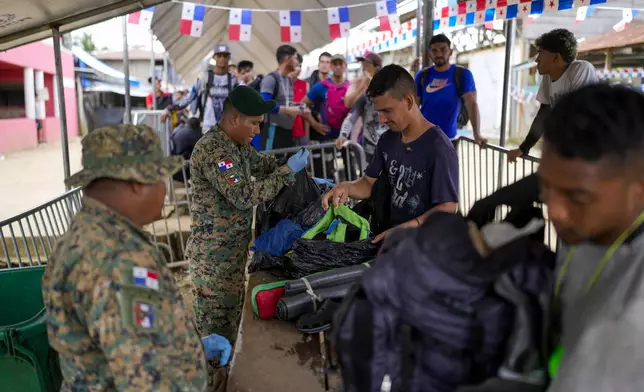 Panamanian police inspect the bags of migrants who arrived in Bajo Chiquito Panama, after crossing the Darien Gap from Colombia in hopes of reaching the United States, Friday, Nov. 8, 2024. (AP Photo/Matias Delacroix)