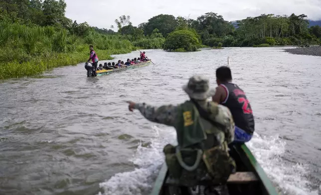 Panamanian border police stop a boat transporting migrants who walked across the Darien Gap from Colombia on their way north to the United States, along the Tuquesa River, near Bajo Chiquito, Panama, Saturday, Nov. 9, 2024. (AP Photo/Matias Delacroix)