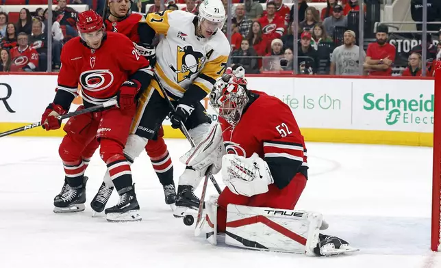 Carolina Hurricanes goaltender Pyotr Kochetkov (52) controls the puck in front of Pittsburgh Penguins' Evgeni Malkin (71) and Hurricanes William Carrier (28) during the first period of an NHL hockey game in Raleigh, N.C., Thursday, Nov. 7, 2024. (AP Photo/Karl B DeBlaker)