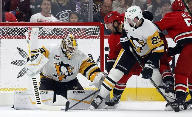 Pittsburgh Penguins goaltender Alex Nedeljkovic (39) tries to freeze the puck with teammate Marcus Pettersson (28) battling Carolina Hurricanes' William Carrier (28) nearby during the first period of an NHL hockey game in Raleigh, N.C., Thursday, Nov. 7, 2024. (AP Photo/Karl B DeBlaker)