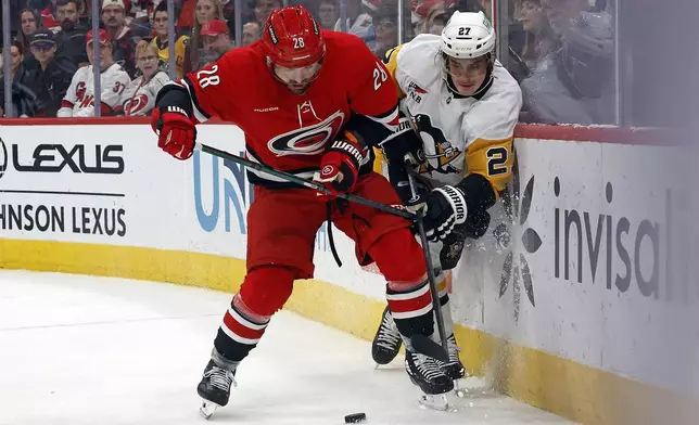 Carolina Hurricanes' William Carrier (28) takes Pittsburgh Penguins' Ryan Graves (27) off the puck during the second period of an NHL hockey game in Raleigh, N.C., Thursday, Nov. 7, 2024. (AP Photo/Karl B DeBlaker)