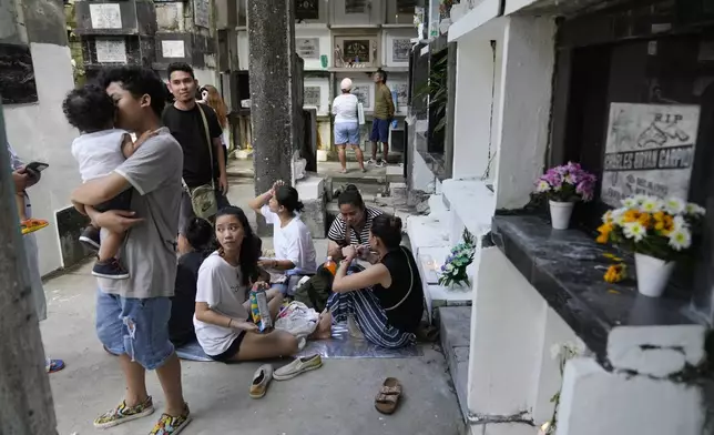 A family gathers in front of the tomb of their loved one at Manila's North Cemetery, Philippines as the nation observes All Saints Day on Friday, Nov. 1, 2024. (AP Photo/Aaron Favila)