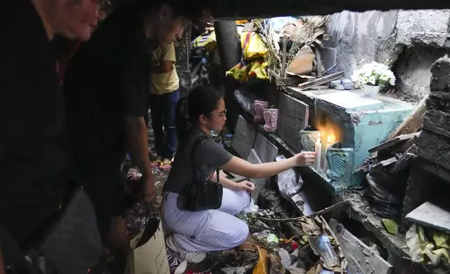 A family lights candles as they visit the tomb of their departed loved one at Manila's North Cemetery, Philippines as the nation observes All Saints Day on Friday, Nov. 1, 2024. (AP Photo/Aaron Favila)