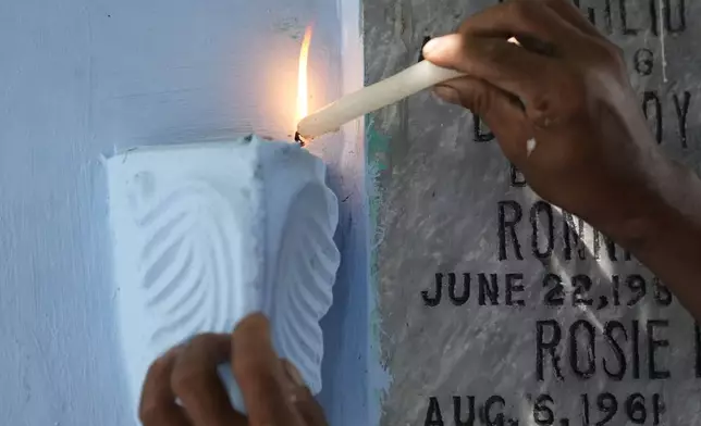 A man lights candles at the tomb of departed loved ones at Manila's North Cemetery, Philippines as the nation observes All Saints Day on Friday, Nov. 1, 2024. (AP Photo/Aaron Favila)