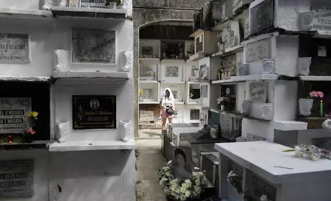 A woman stands in between apartment-type tombs at Manila's North Cemetery, Philippines as the nation observes All Saints Day on Friday, Nov. 1, 2024. (AP Photo/Aaron Favila)