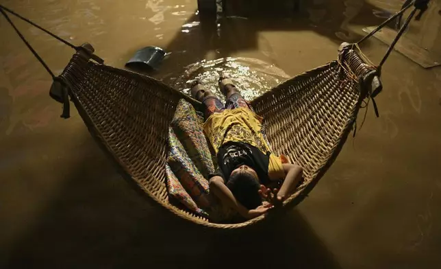 A boy tries to sleep in his flooded house after Typhoon Yinxing, locally called Marce, blew past Buguey town, Cagayan province, northern Philippines on Friday Nov. 8, 2024. (AP Photo/Noel Celis)