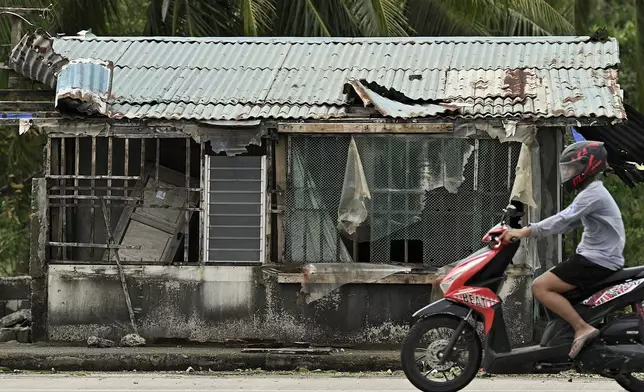 A resident passes by a damaged house after Typhoon Yinxing, locally called Marce, blew past Aparri town, Cagayan province, northern Philippines on Friday, Nov. 8, 2024. (AP Photo/Noel Celis)