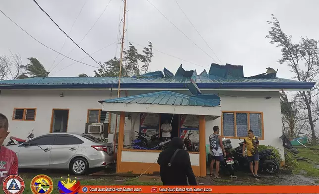 In this photo provided by Philippine Coast Guard, its members stand outside their damaged building due to Typhoon Yinxing in Santa Ana, Cagayan province, northern Philippines Thursday Nov. 7, 2024. (Philippine Coast Guard via AP)