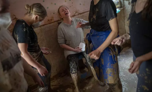 Dolores Merchan, 67, reacts in tears as she is assisted by volunteers clearing mud from her home, where she has lived all her life with her husband and three children, and which has been severely affected by the floods in Masanasa, Valencia, Spain, Thursday, Nov. 7, 2024. (AP Photo/Emilio Morenatti)