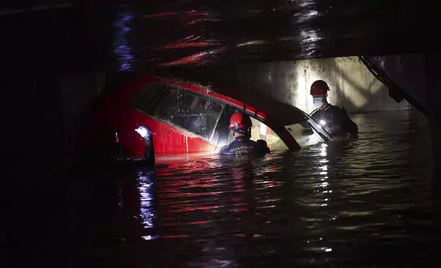 Civil Guards check cars for bodies in an indoor car park after floods in Paiporta, near Valencia, Spain, Monday, Nov. 4, 2024. (AP Photo/Alberto Saiz)