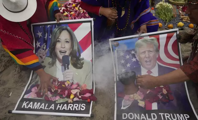 Shamans perform a good luck ritual holding posters of Democratic presidential nominee Vice President Kamala Harris and Republican presidential nominee former President Donald Trump, at the beach in Lima, Peru, Tuesday, Nov. 5, 2024. (AP Photo/Martin Mejia)