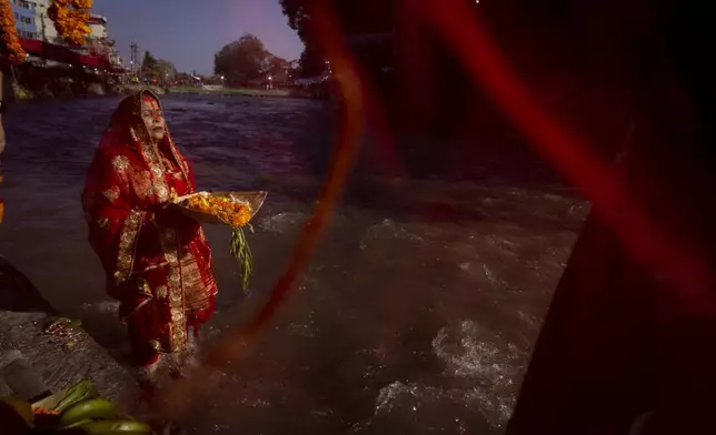 A Nepalese woman offers prayers to the setting sun on the bank of Bagmati River during the Chhath Puja festival in Kathmandu, Nepal, Thursday, Nov. 7, 2024. (AP Photo/Niranjan Shrestha)