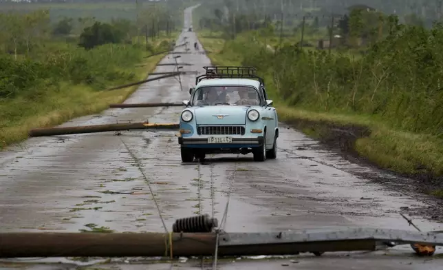 People drive along a road littered with fallen power lines after the passing of Hurricane Rafael in San Antonio de los Banos, Cuba, Thursday, Nov. 7, 2024. (AP Photo/Ramon Espinosa)