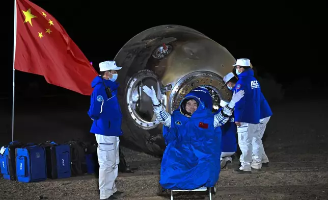 In this photo released by Xinhua News Agency, astronaut Ye Guangfu waves near the re-entry capsule of the Shenzhou-18 manned space mission after it landed successfully at the Dongfeng landing site in northern China's Inner Mongolia Autonomous Region in the early Monday, Nov. 4, 2024. (Li Xin/Xinhua via AP)