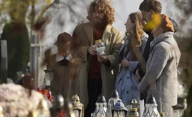 A man lights a candle at a grave on All Saints' Day, a time for reflecting on those who have died, in Zakroczym near Warsaw, Polan, on Friday Nov. 1, 2024. (AP Photo/Czarek Sokolowski)