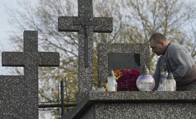 A man cleans a grave on All Saints' Day, a time for reflecting on those who have died, in Zakroczym near Warsaw, Poland, on Friday Nov. 1, 2024. (AP Photo/Czarek Sokolowski)