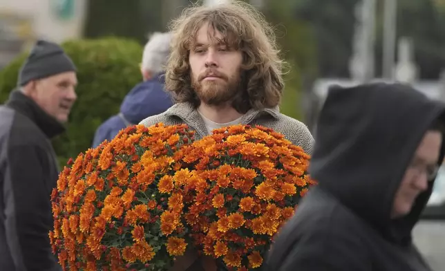 People prepare for All Saints' Day at the cemetery in Zakroczym, near Warsaw, Poland, Wednesday, Oct. 30, 2024. (AP Photo/Czarek Sokolowski)