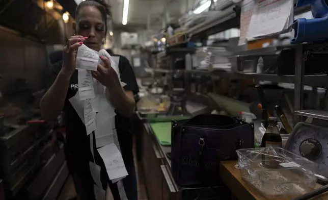 April Youst goes through dinner orders in the kitchen while working at a restaurant in West Virginia on Wednesday, Oct. 9, 2024. (AP Photo/Carolyn Kaster)