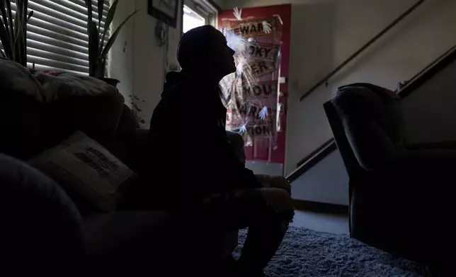 April Youst is silhouetted as she sits on her living room sofa in West Virginia on Wednesday, Oct. 9, 2024. (AP Photo/Carolyn Kaster)