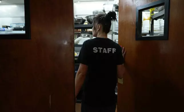 April Youst enters the kitchen of a restaurant where she works, Wednesday, Oct. 9, 2024, in West Virginia. (AP Photo/Carolyn Kaster)