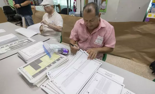 An election official sorts ballots during general elections in San Juan, Puerto Rico, Tuesday, Nov. 5, 2024. (AP Photo/Alejandro Granadillo)