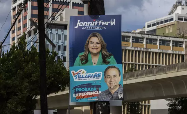 A campaign poster promotes New Progressive Party gubernatorial candidate and Puerto Rico’s representative in Congress Jenniffer González, above a campaign poster of resident commissioner candidate Luis Villafañe, defaced with the Spanish words for corrupt and rogue, in San Juan, Puerto Rico, Saturday, Nov. 2, 2024. (AP Photo/Alejandro Granadillo)