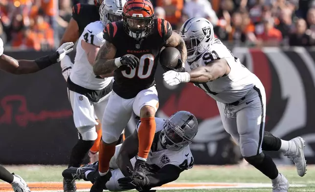 Cincinnati Bengals running back Chase Brown (30) runs against Las Vegas Raiders linebacker Robert Spillane (41), defensive end K'Lavon Chaisson (44) and defensive tackle Matthew Butler (91) during the first half ofan NFL football game in Cincinnati, Sunday, Nov. 3, 2024. (AP Photo/Jeff Dean)