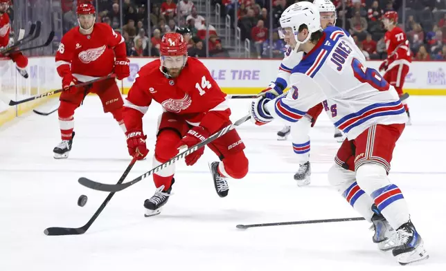 New York Rangers defenseman Zac Jones (6) clears the puck against Detroit Red Wings center Tyler Motte (14) during the first period of an NHL hockey game Saturday, Nov. 9, 2024, in Detroit. (AP Photo/Duane Burleson)