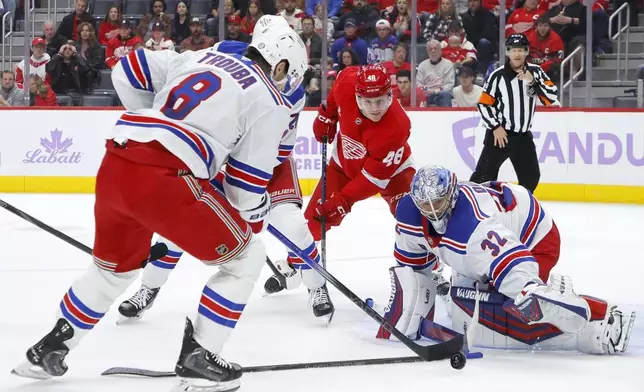 New York Rangers defenseman Jacob Trouba (8) clears the puck away from goaltender Jonathan Quick (32) after a shot by Detroit Red Wings right wing Jonatan Berggren (48) during the first period of an NHL hockey game Saturday, Nov. 9, 2024, in Detroit. (AP Photo/Duane Burleson)