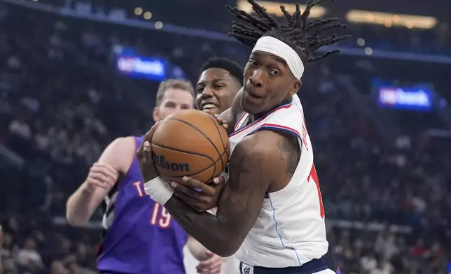 Los Angeles Clippers guard Terance Mann grabs a rebound in front of Toronto Raptors guard RJ Barrett (9) during the first half of an NBA basketball game Saturday, Nov. 9, 2024, in Inglewood, Calif. (AP Photo/Marcio Jose Sanchez)