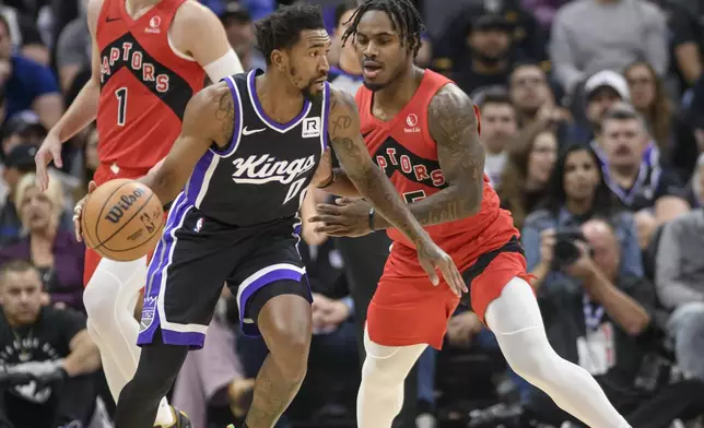 Sacramento Kings guard Malik Monk (0) is guarded by Toronto Raptors guard Davion Mitchell during the first half of an NBA basketball game in Sacramento, Calif., Wednesday, Nov. 6, 2024. (AP Photo/Randall Benton)