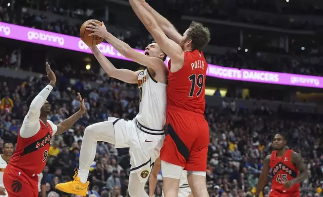 Denver Nuggets guard Christian Braun, center, drives to the basket as Toronto Raptors guard RJ Barrett, left, and center Jakob Poeltl (19) defend in the first half of an NBA basketball game Monday, Nov. 4, 2024, in Denver. (AP Photo/David Zalubowski)