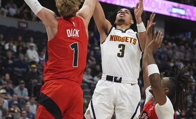 Denver Nuggets guard Julian Strawther, center, goes up to shoot as Toronto Raptors guards Gradey Dick, left, and Ja'Kobe Walter, right, defend in the first half of an NBA basketball game Monday, Nov. 4, 2024, in Denver. (AP Photo/David Zalubowski)