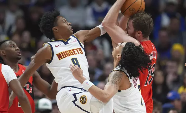 Toronto Raptors center Jakob Poeltl, back right, pulls in a rebound as Denver Nuggets forward Peyton Watson, left, and guard Julian Strawther defend in the first half of an NBA basketball game Monday, Nov. 4, 2024, in Denver. (AP Photo/David Zalubowski)