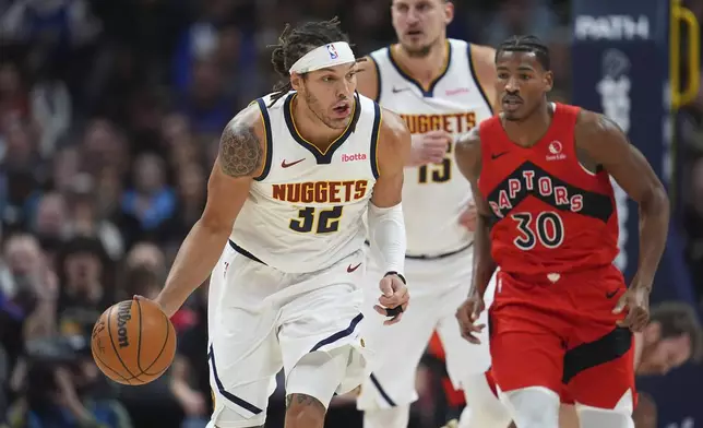 Denver Nuggets forward Aaron Gordon, left, collects the ball as Toronto Raptors guard Ochai Agbaji, right, and Nuggets center Nikola Jokic, center, pursue in the first half of an NBA basketball game Monday, Nov. 4, 2024, in Denver. (AP Photo/David Zalubowski)