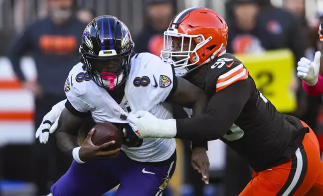 Cleveland Browns defensive end Za'Darius Smith (99) sacks Baltimore Ravens quarterback Lamar Jackson (8) during the second half of an NFL football game in Cleveland, Sunday, Oct. 27, 2024. (AP Photo/David Richard)