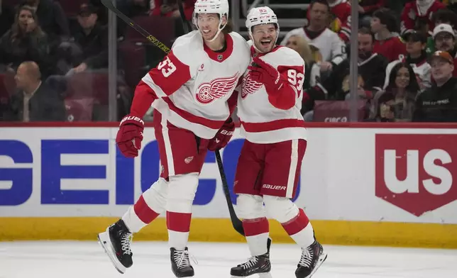 Detroit Red Wings defenseman Moritz Seider, left, and right wing Alex DeBrincat celebrate after DeBrincat scored on the Chicago Blackhawks during the first period of an NHL hockey game Wednesday, Nov. 6, 2024, in Chicago. (AP Photo/Erin Hooley)